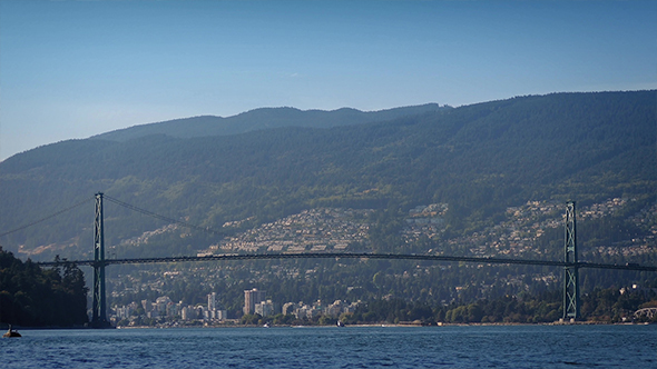 Busy Suspension Bridge Over Water To The Mountains