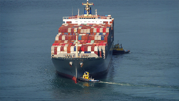Tug Boats Pushing Freighter Around At Sea