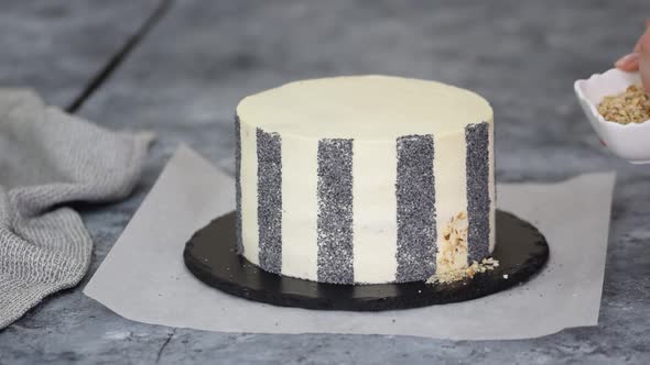 Unrecognizable Woman Pastry Chef Decorating Cake with Walnut and Poppy Seeds