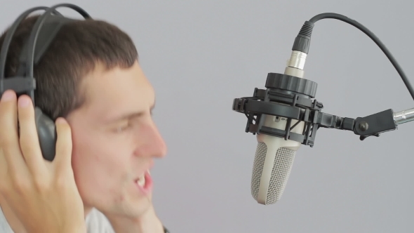 Man In Headphones Singing At Studio Microphone.