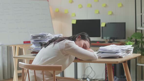 Back View Of Asian Woman Sleeping While Working Hard With Documents At The Office