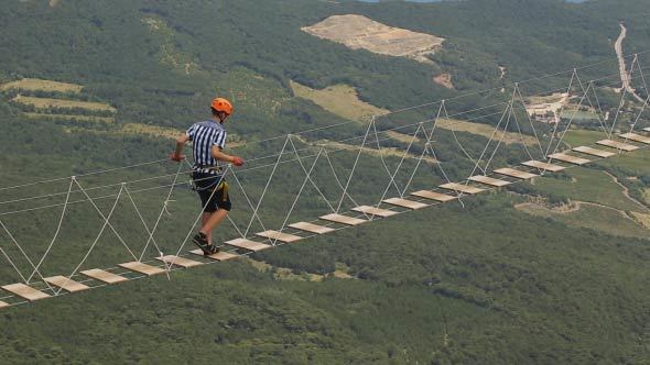 Man Walking A Dangerous Suspension Bridge