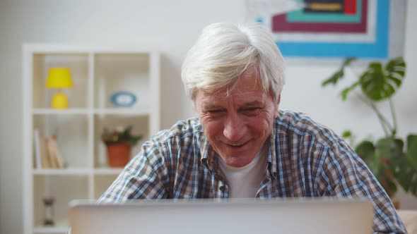 Smiling Senior Man Talk on Video Call on Laptop at Home