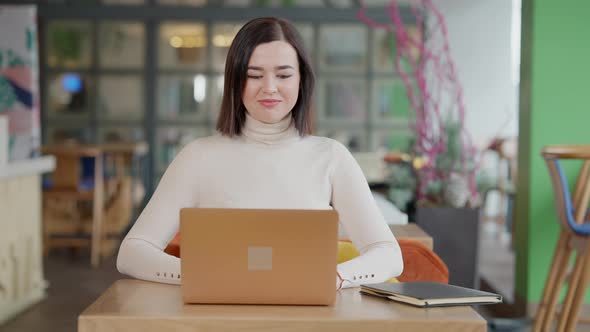 Excited Happy Young Woman Making Victory Gesture Sitting in Cafe with Laptop