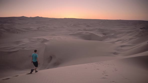 Man walking on a desert dune on an adventure travel holiday at sunset, Peru