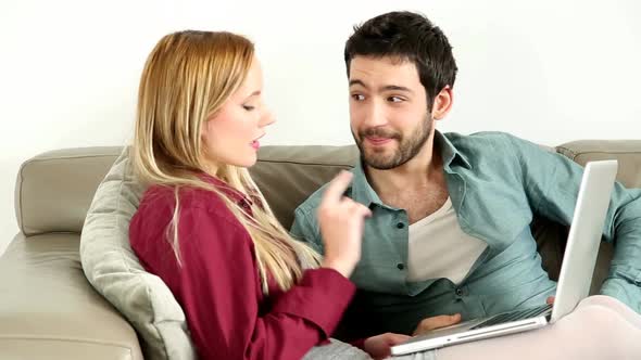 Young Couple Lounging On Couch With Laptop At Home 1