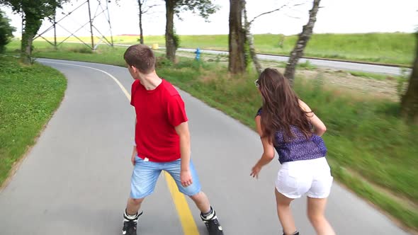 Young Woman And Man Rollerblading And Performing In Park On A Beautiful Warm Day, Holding Hands. 1 alt