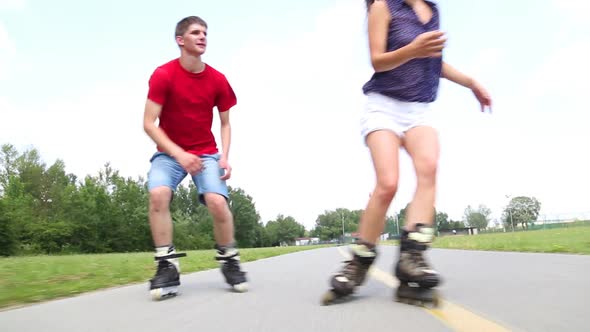 Young Woman And Man Rollerblading And Performing In Park On A Beautiful Warm Day.
