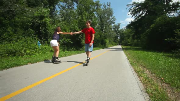 Couple Rollerbladers Skating Towards Camera In Park. 3