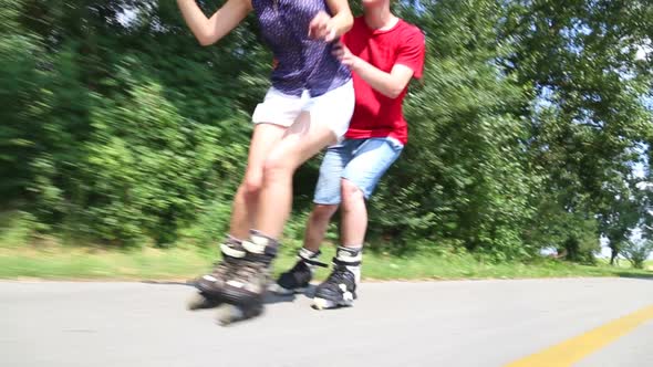Happy Young Couple Rollerblading On A Wonderful Sunny Day In Park, Holding Her Waist alt