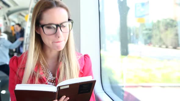 Cute Blond Woman Reading Book While Driving In Tram alt