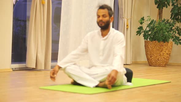 Indian Man Sitting On Green Mat And Practicing Yoga 1