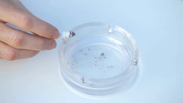 Male Hand Stubbing Out Cigarette In Glass Ashtray alt