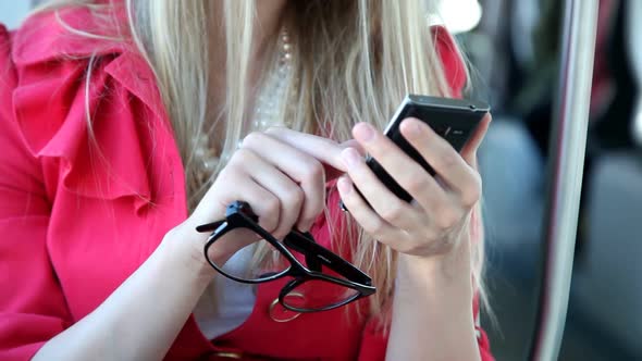 Blond Girl Sitting In Tram, Close Up On Mobile, Phone, Cell, Holding Glasses