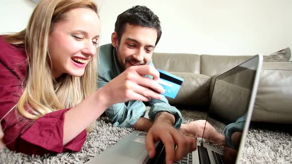 Blond Woman Holding Credit Card While She's Doing Online Shopping With Partner