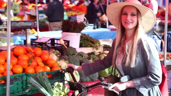 Blonde Girl With Bike Is Walking At The Market, Smiling