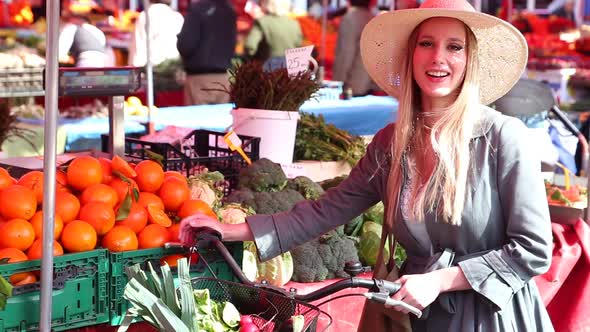 Blonde Girl With Bike Standing At The Market, Smiling