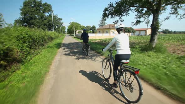 Slow Motion - Retired Couple Cycling On Road In Village In France 2 alt