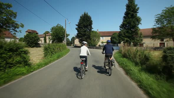 Slow Motion - Retired Couple Cycling On Road In Village In France 3 alt