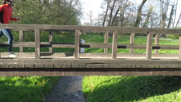 Slow Motion Of Runner Crossing A Bridge In Park. 2