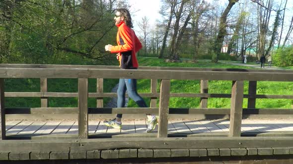 Slow Motion Of Runner Crossing A Bridge In Park. 3