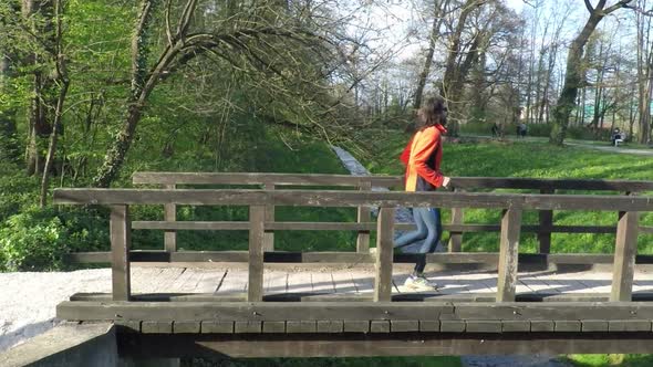 Slow Motion Of Runner Crossing A Bridge In Park. 4