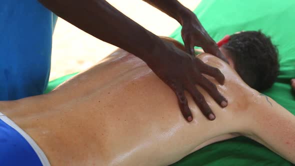 Sri Lankan Man Giving Shoulder Oil Massage To Caucasian Man 2