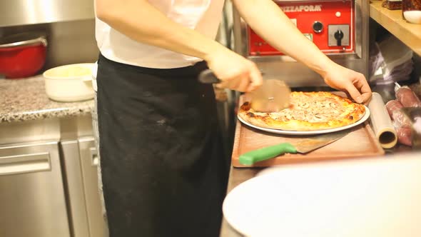 Chef Cutting Pizza In Half