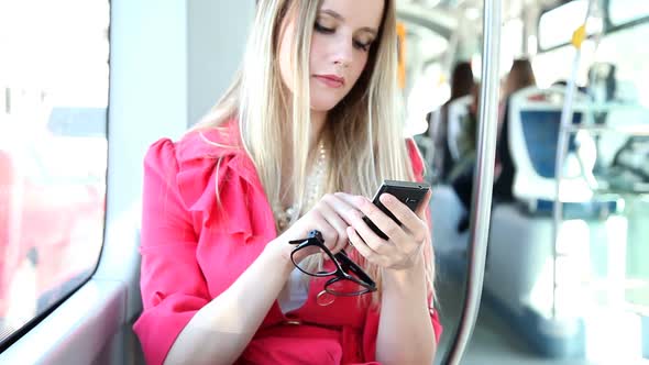 Young Blond Woman Riding Tram, Typing On Mobile, Phone, Cell, Holding Glasses 2