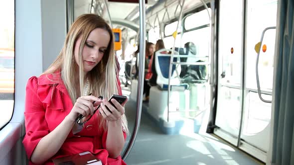 Young Blond Woman Riding Tram, Typing On Mobile, Phone, Cell, Holding Glasses 4 alt