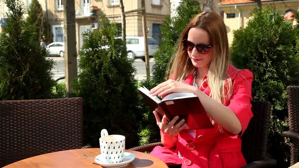 Young Blond Woman Sitting In Coffee Shop, Reading Book 2 alt