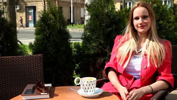 Young Blond Woman Sitting On Chair In Coffee Shop,