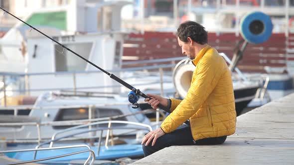 Man In Yellow Jacket Sitting On The Dock Fishing