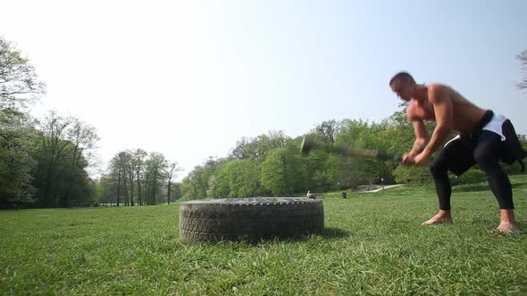 Muscular Man Hitting Tire With A Hammer 4