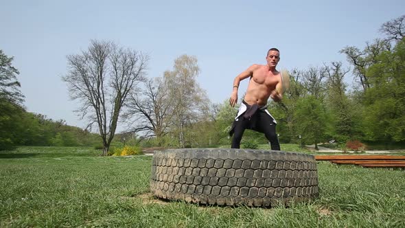 Muscular Man Hitting Tire With A Hammer With Only One Hand 1