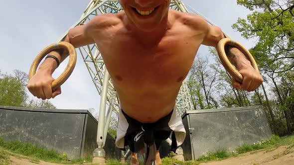 Muscular Man Is Doing Push-Ups On Gymnastics Rings alt