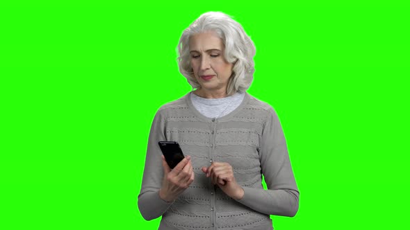 Smiling Senior Woman with Smartphone on Green Screen