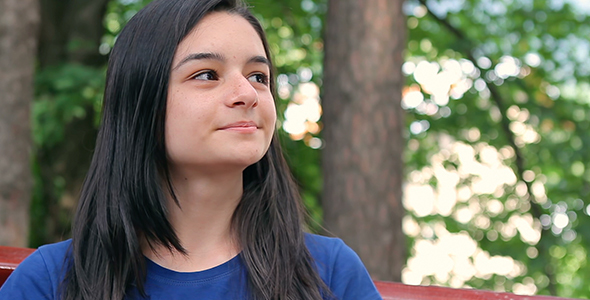 Smiling Teenager Girl Relaxing in Park  alt