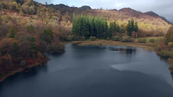 Aerial footage of Yew Tree Tarn in Cumbria in Autumn with the trees in colour.