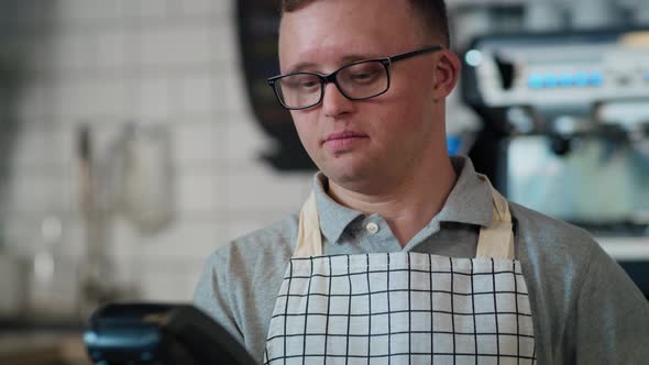 Caucasian man with down syndrome accepting contactless payment in the cafe. Shot with RED helium cam