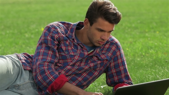 Male Relaxing In His Garden Using Laptop