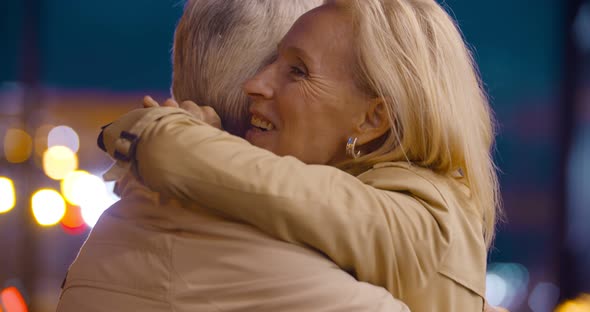 Bokeh Shot of Happy Senior Couple Hugging in City at Night