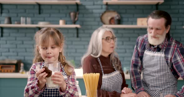 Senior Grandparents Couple with Dgranddaughter Cooking in Kitchen