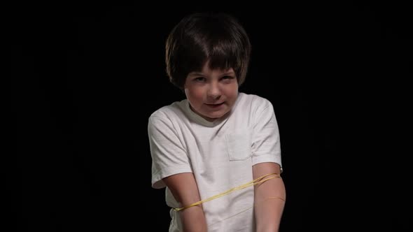 Portrait of Caucasian Boy Trying Free Himself From Ropes Looking at Camera