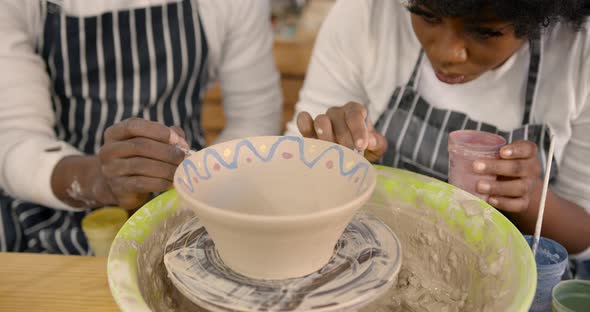 Black Couple Decorating Plate in Workshop During Class