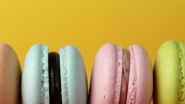 Multicolor Macarons, French macaroon, sweet tasty desserts. Isolated on a yellow background.