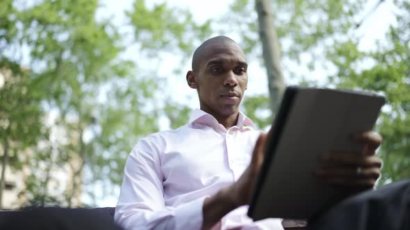 Serious African businessman typing by tablet