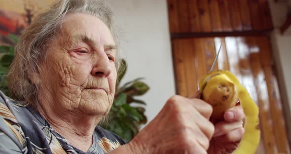 an Elderly Woman a Grandmother an Old Woman Peeling Potatoes with a Knife in Her House a Purposeful