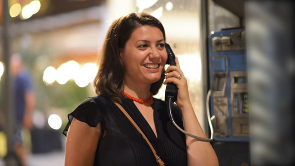 Woman Talking at Public Telephone