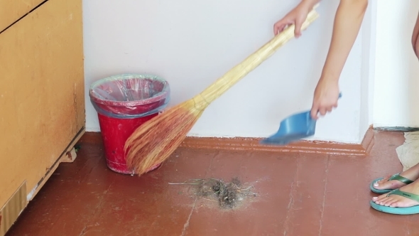 Girl With a Broom Sweeps Debris On The Floor